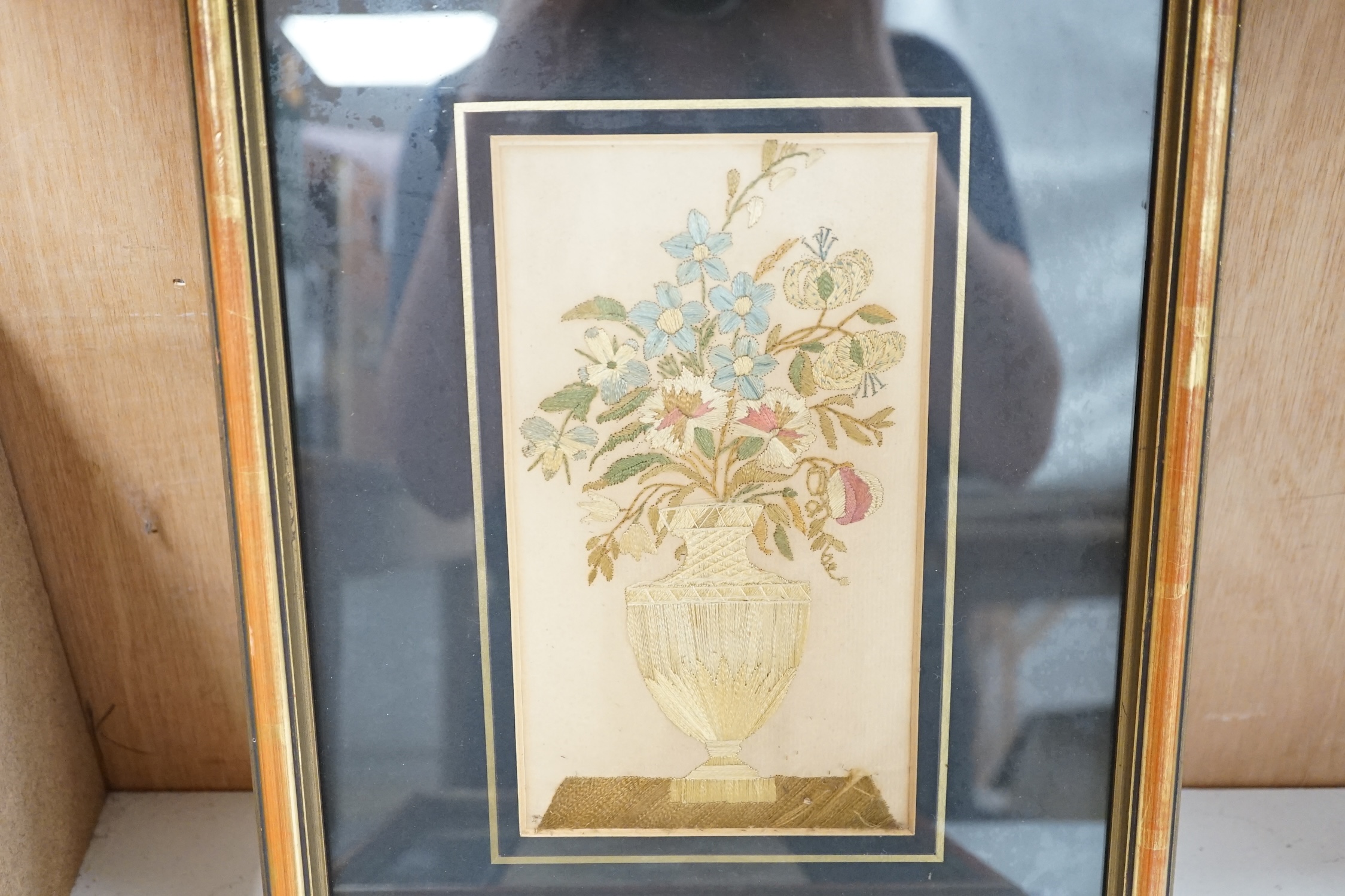Two framed 19th century silk embroidered panels, one of flowers in a classical shaped vase, the other a ribboned posy of flowers, tallest 20.5cm high. Condition - some faint staining to backing and colour of silks